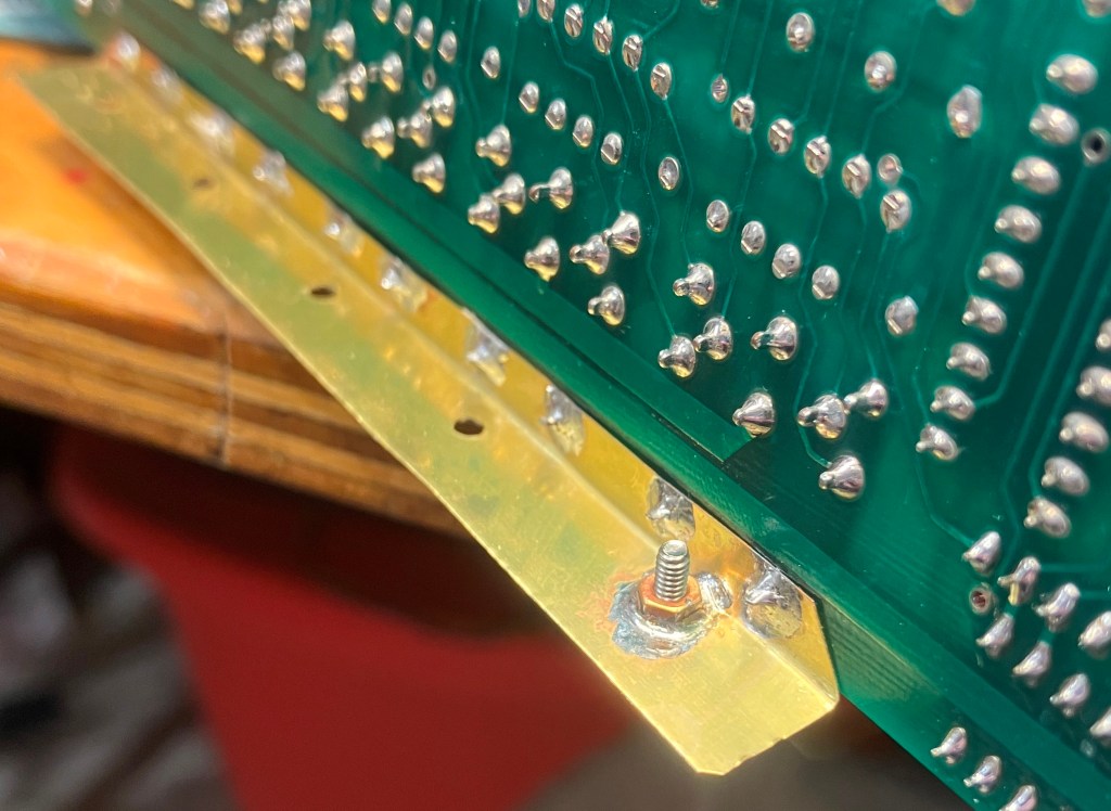 Brass-angle showing the fixturing used to solder the prass nuts to the brass angle.